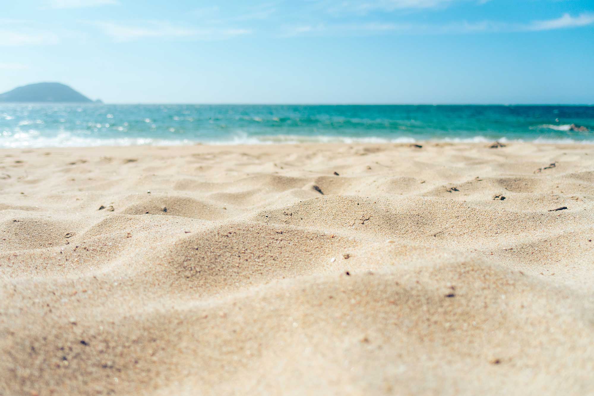 En strandscen fotograferad i närbild på den finkorniga, gulvita sanden